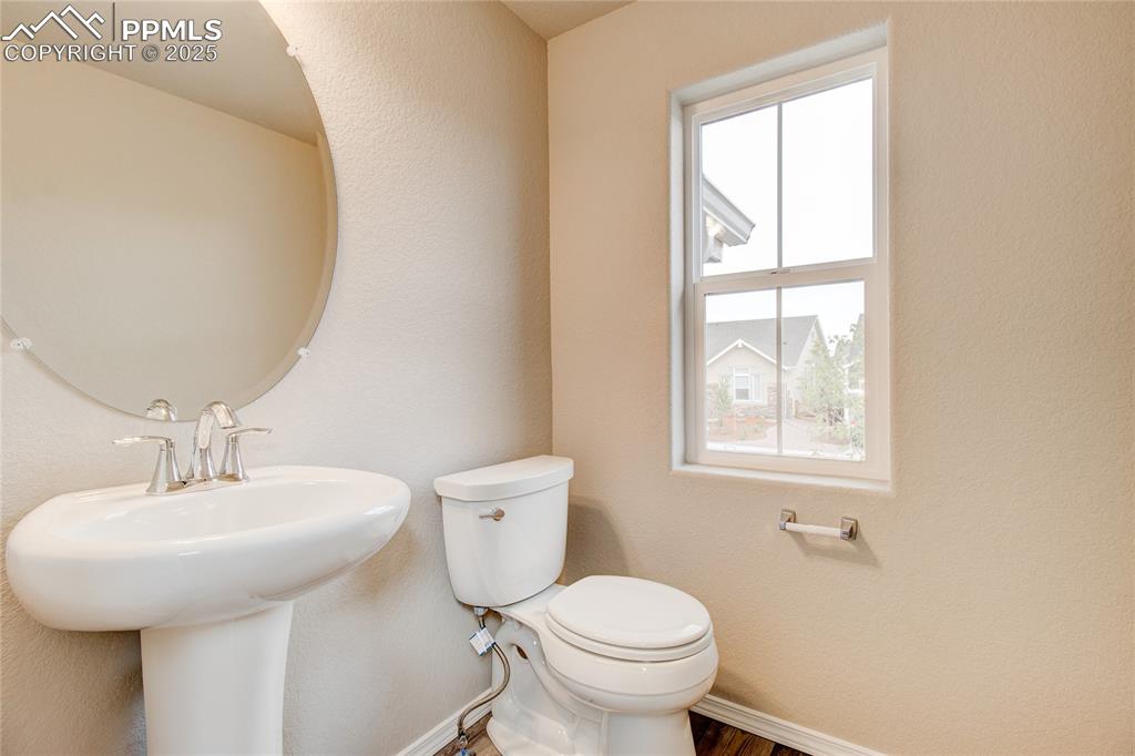 Half bathroom with a textured wall and wood finished floors