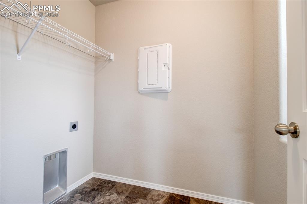 Laundry room with electric dryer hookup and stone finish flooring