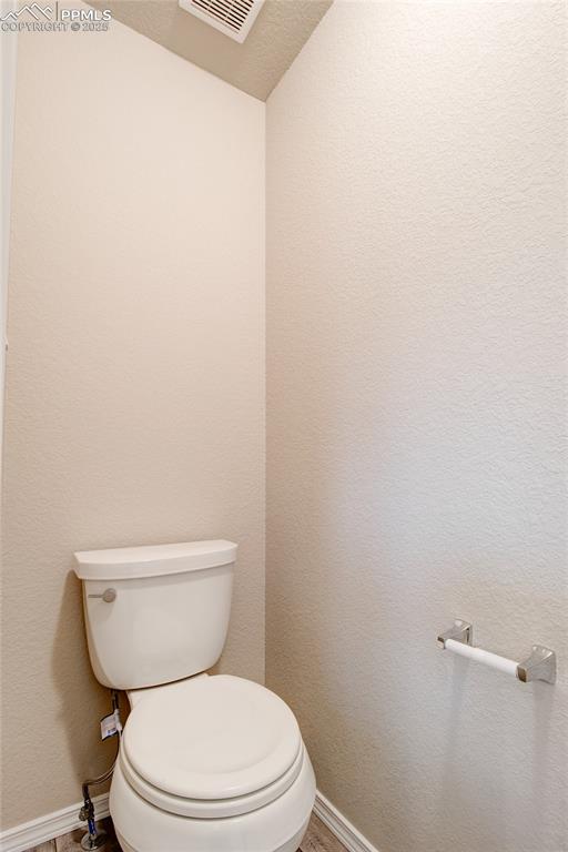 Bathroom featuring a textured wall and a textured ceiling