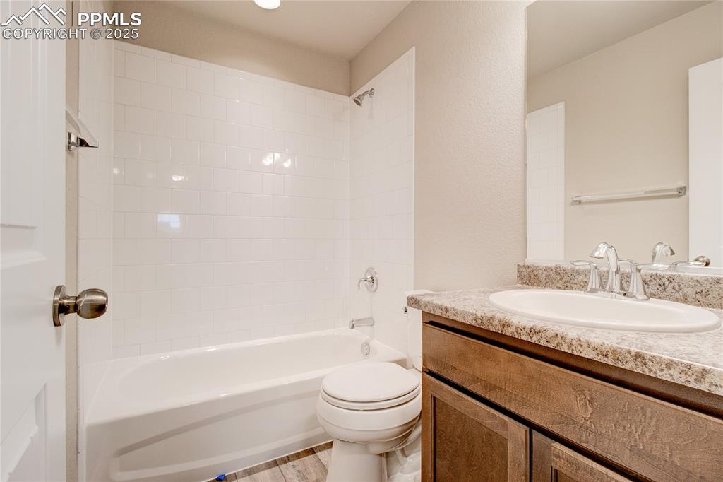 Full bath with shower / bathtub combination, vanity, and light wood-type flooring