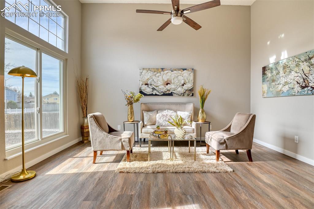 Living area featuring a high ceiling, light wood-style floors, and a ceiling fan