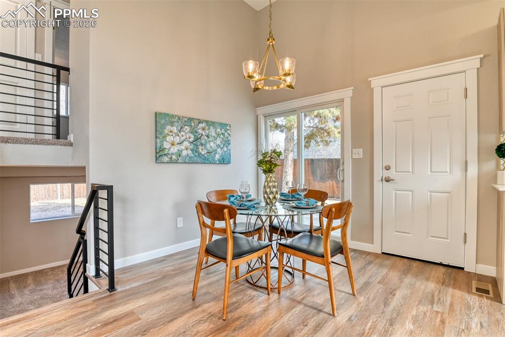 Dining area with a high ceiling, hanging lights, and light wood-style floors