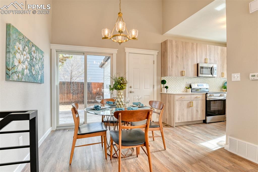 Dining room with suspended lighting, light wood-style floors, and a high ceiling