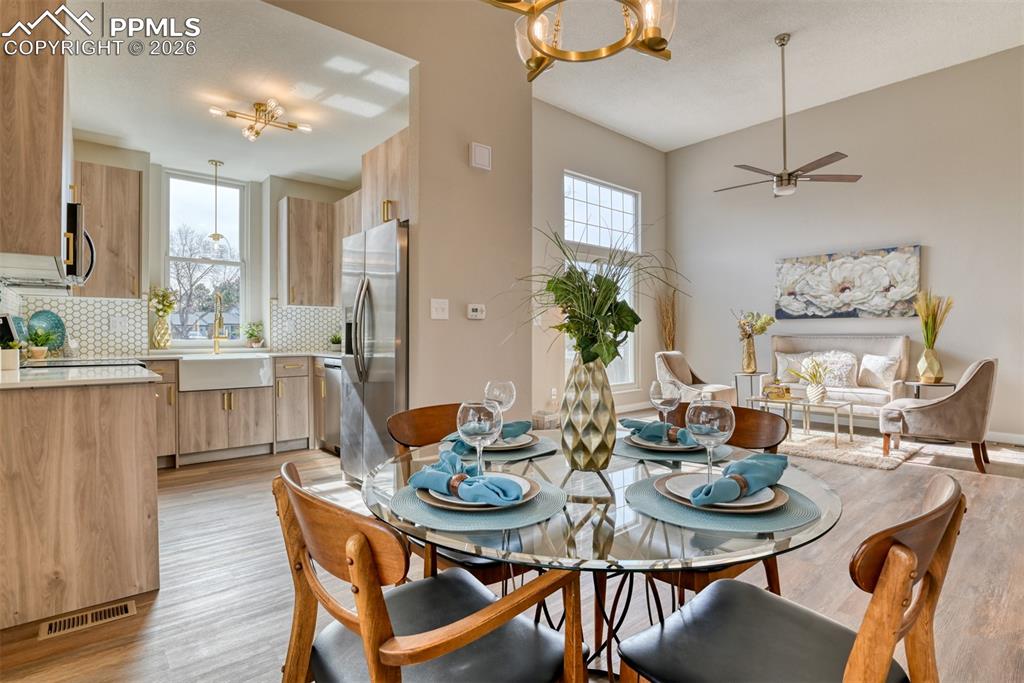 Dining area with ceiling fan, hanging lights, and light wood finished floors