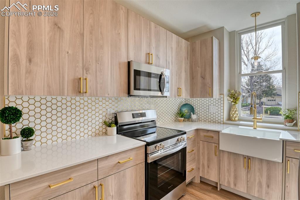 Kitchen with stainless steel appliances, light stone counters, modern cabinets, and light wood finish cabinets