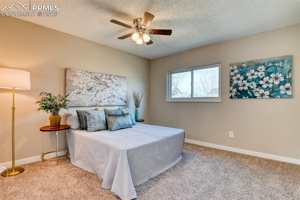 Carpeted bedroom featuring a ceiling fan and a textured ceiling