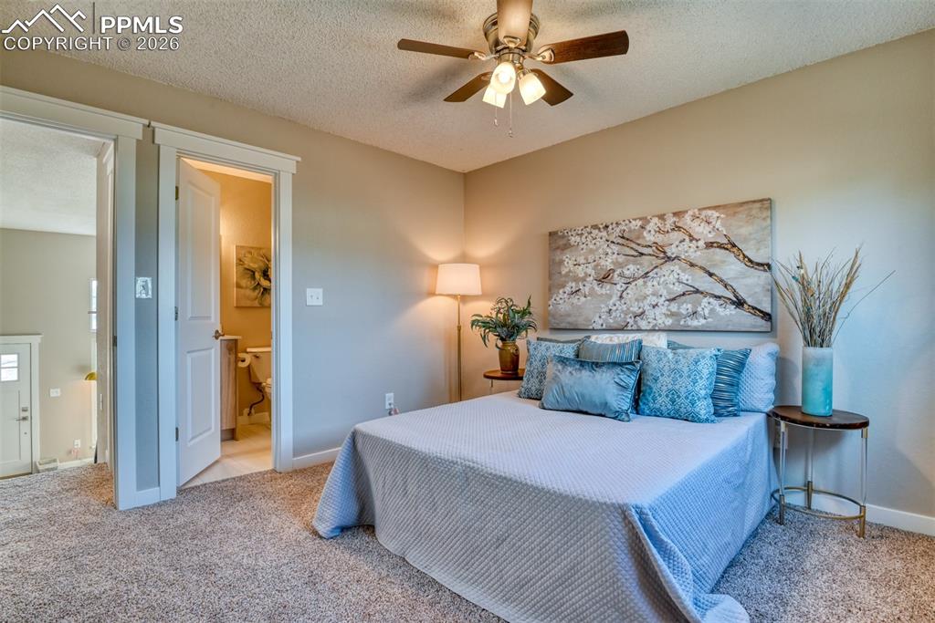 Bedroom with a textured ceiling, light colored carpet, and a ceiling fan