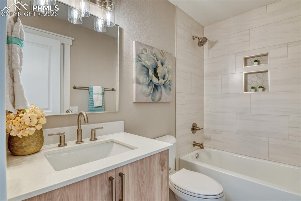 Full bathroom featuring vanity, washtub / shower combination, and a textured wall
