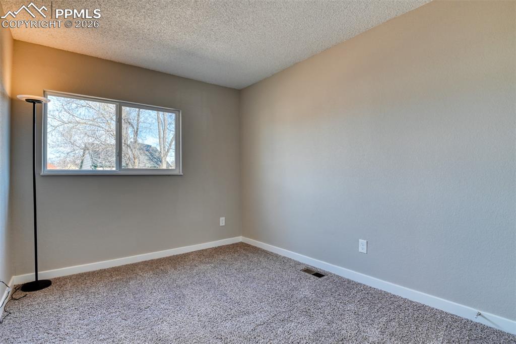 Empty room featuring light colored carpet and a textured ceiling