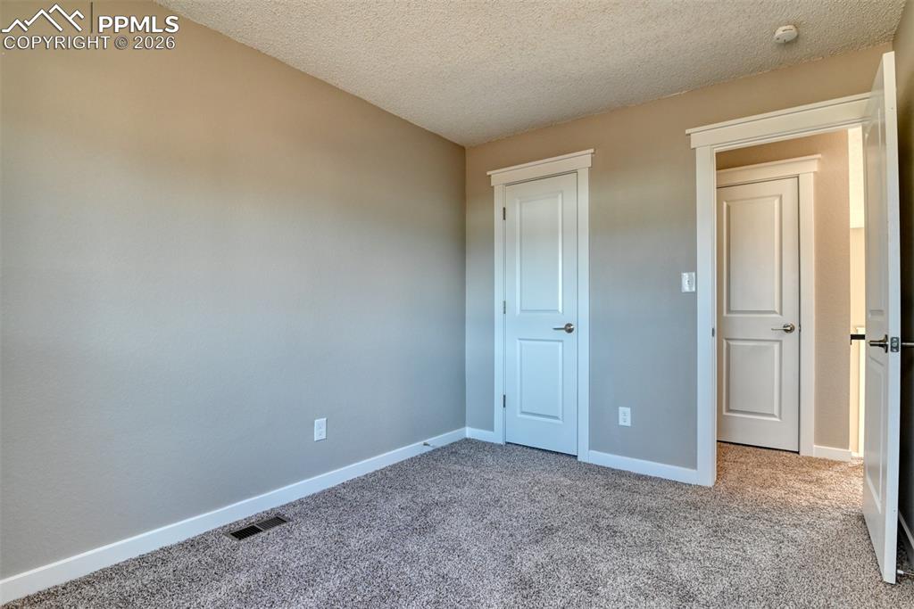 Unfurnished bedroom with carpet flooring, a textured ceiling, and a closet