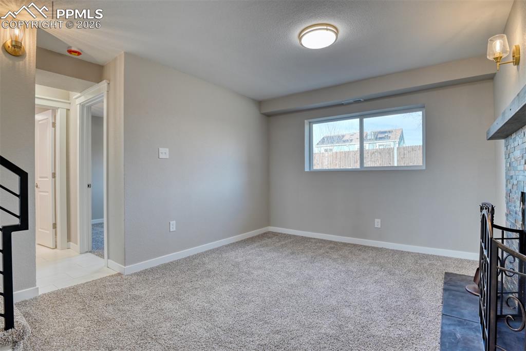 Unfurnished living room featuring light carpet and a fireplace