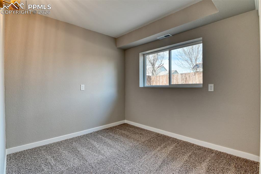Carpeted spare room featuring baseboards