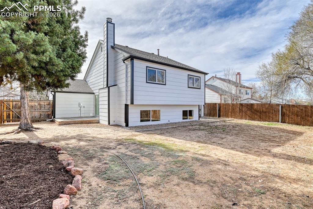 Back of house featuring a fenced backyard, a chimney, and a shingled roof