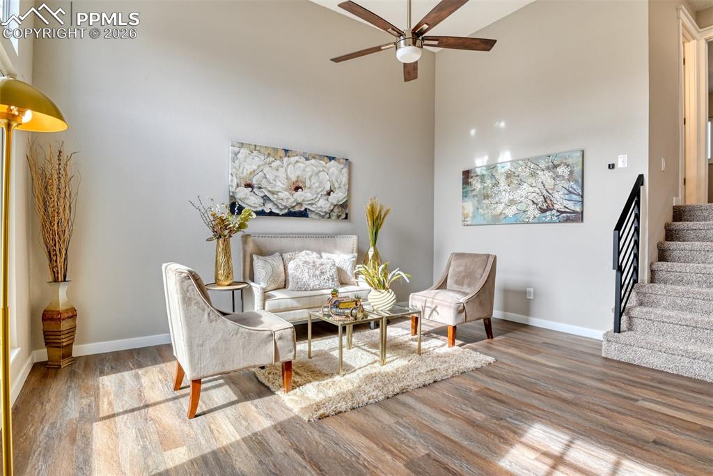 Sitting room with a high ceiling, light wood finished floors, and ceiling fan