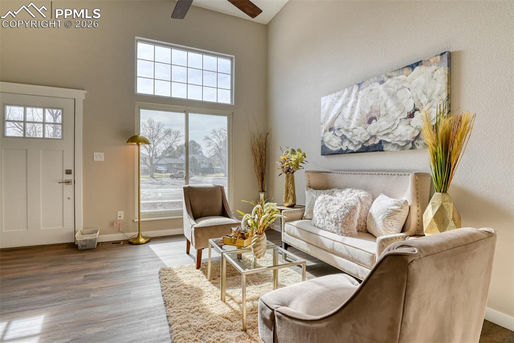 Living room featuring a high ceiling, ceiling fan, and wood finished floors