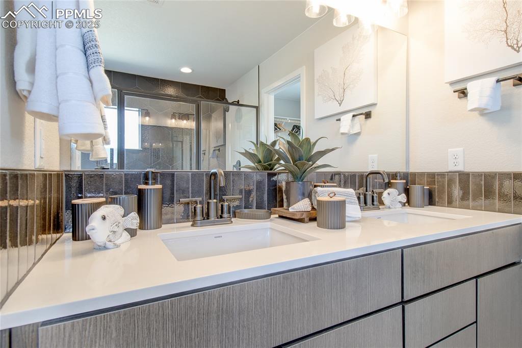 Full bathroom featuring a stall shower, double vanity, and recessed lighting