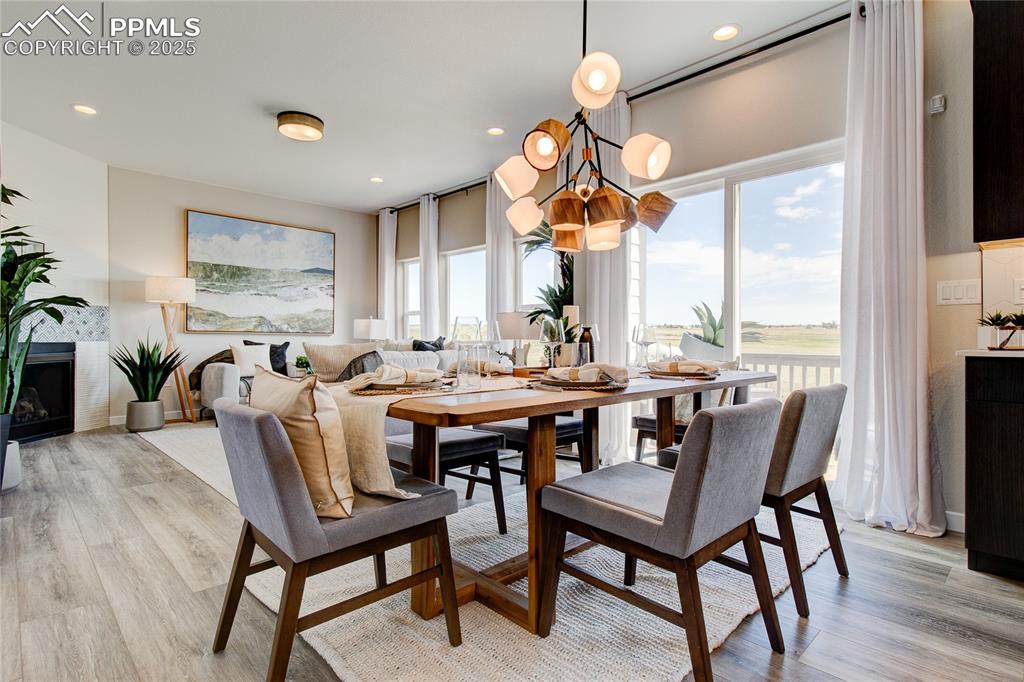 Dining room with light wood-style floors, recessed lighting, a chandelier, and a fireplace