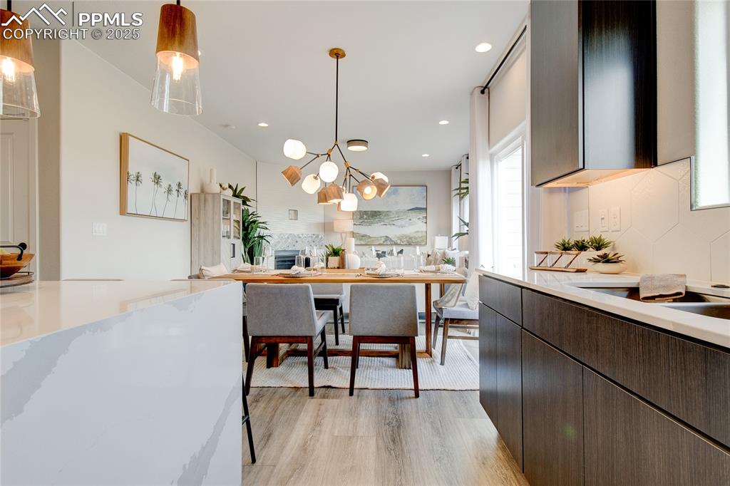 Kitchen featuring decorative light fixtures, light wood finished floors, backsplash, a chandelier, and recessed lighting