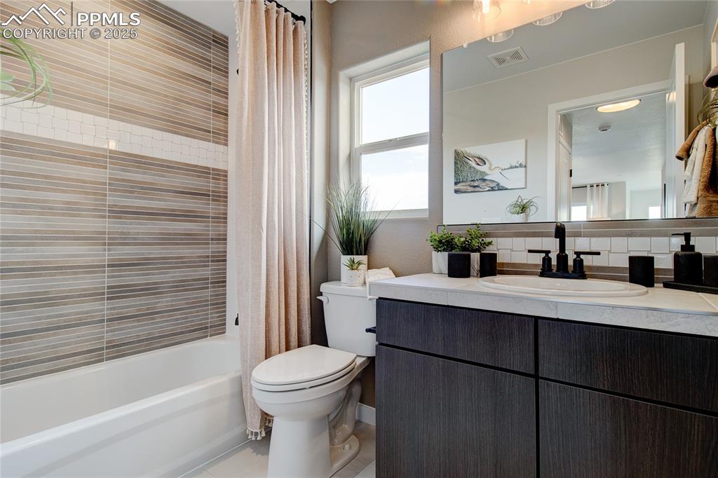 Bathroom featuring vanity, shower / bath combo with shower curtain, and light tile patterned floors