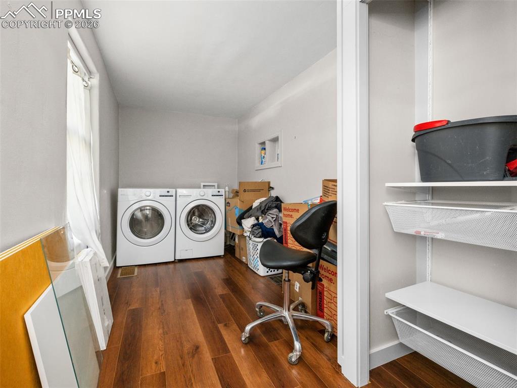 Laundry area with dark wood-style floors and independent washer and dryer