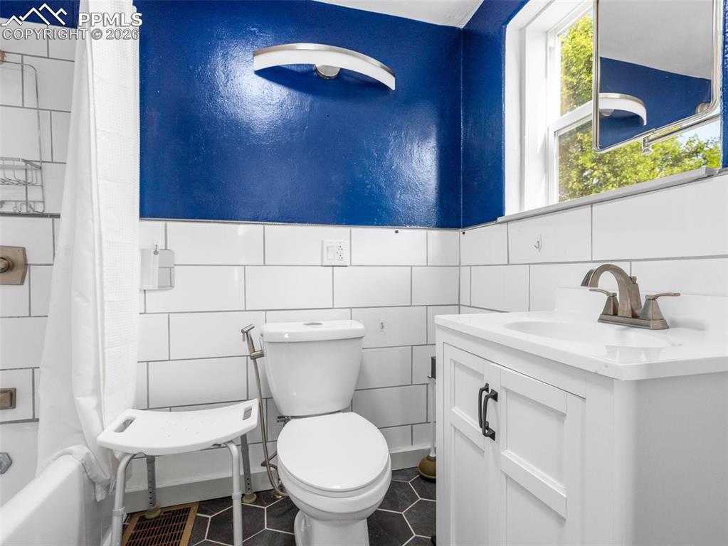 Bathroom with vanity, shower / bath combo, and tile walls