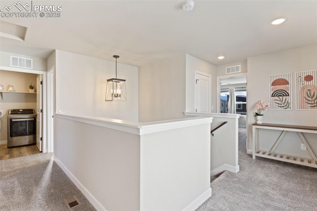 Hallway featuring carpet flooring, washer / dryer, an upstairs landing, and recessed lighting