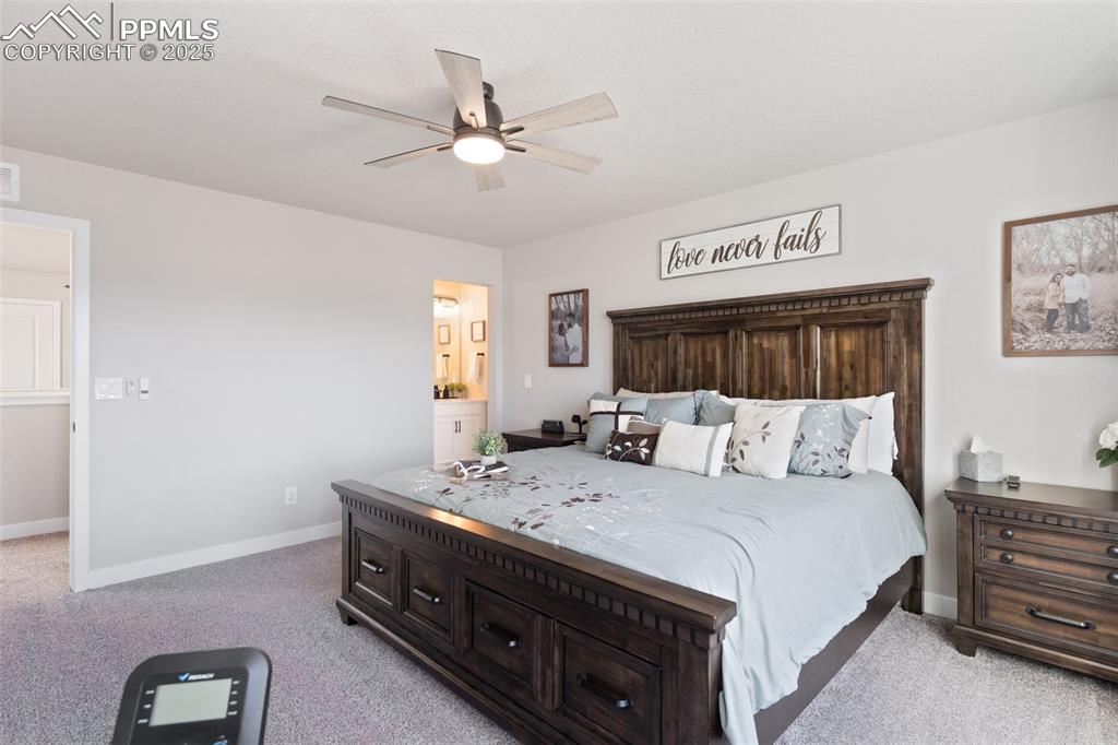 Bedroom featuring light colored carpet, ceiling fan, and ensuite bath