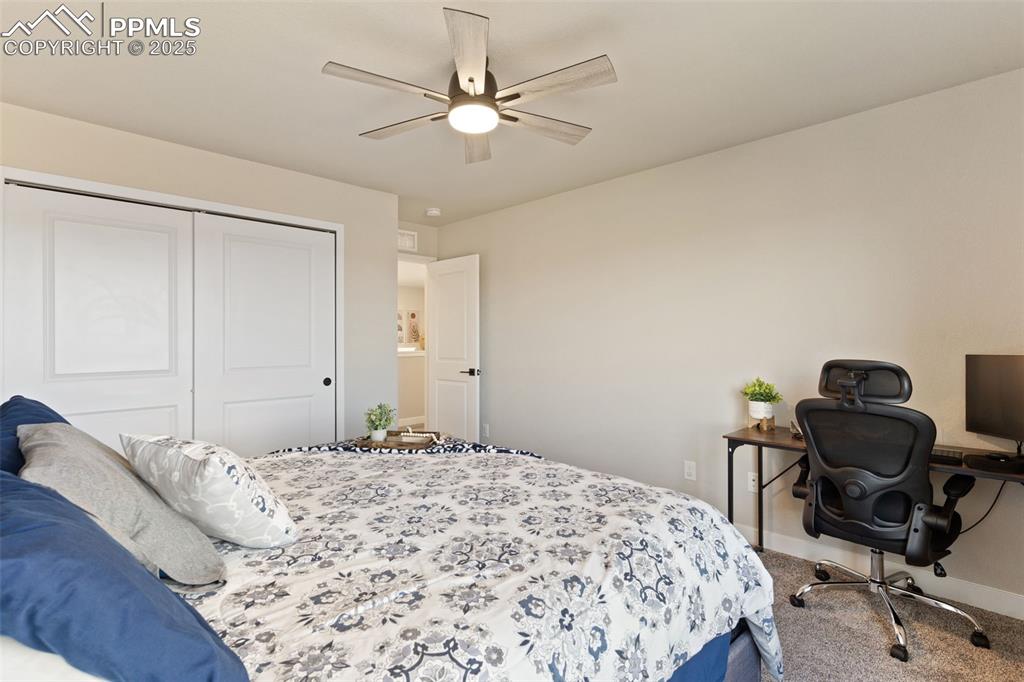 Carpeted bedroom featuring a closet, ceiling fan, and a desk