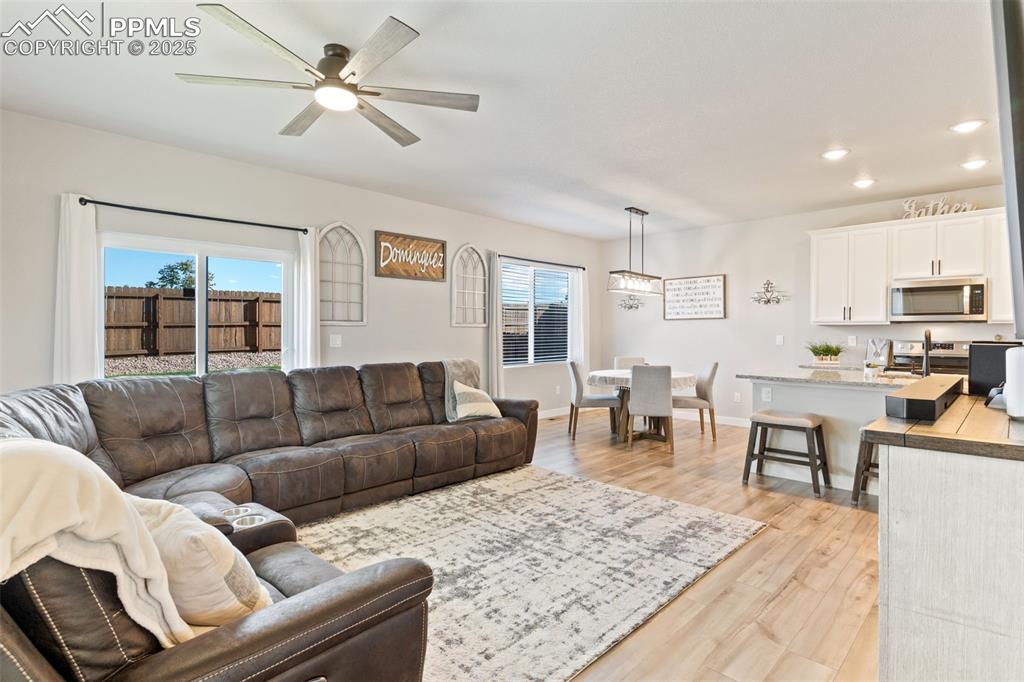 Living room featuring plenty of natural light, light wood-style floors, a ceiling fan, and recessed lighting