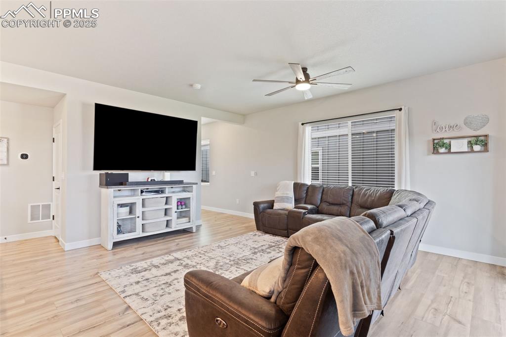 Living area with ceiling fan and light wood-style floors
