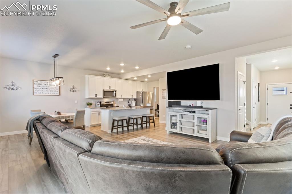 Living area featuring a ceiling fan, light wood-style floors, and recessed lighting