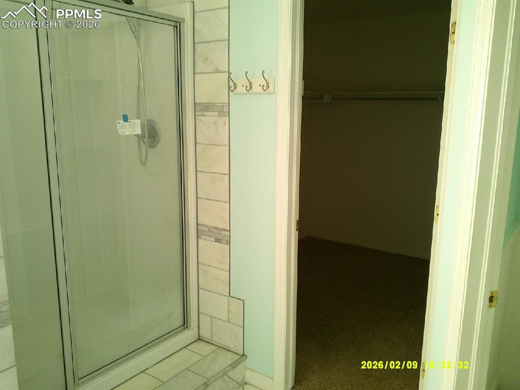 Full bath featuring a stall shower and a spacious closet