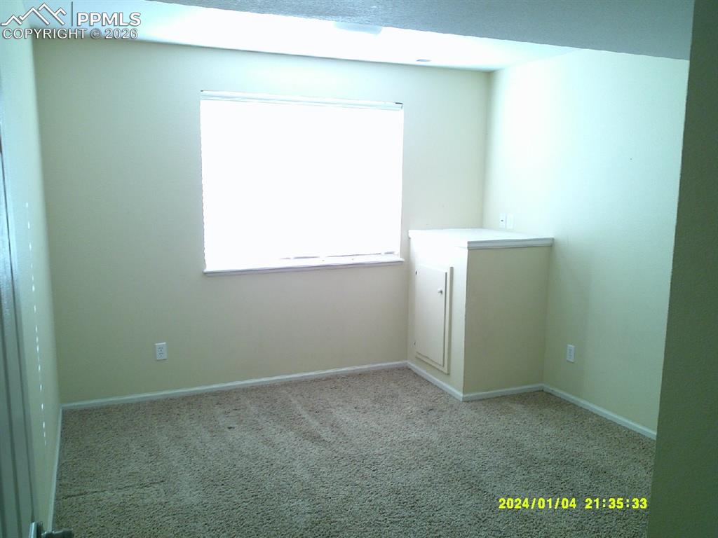 Carpeted spare room featuring baseboards