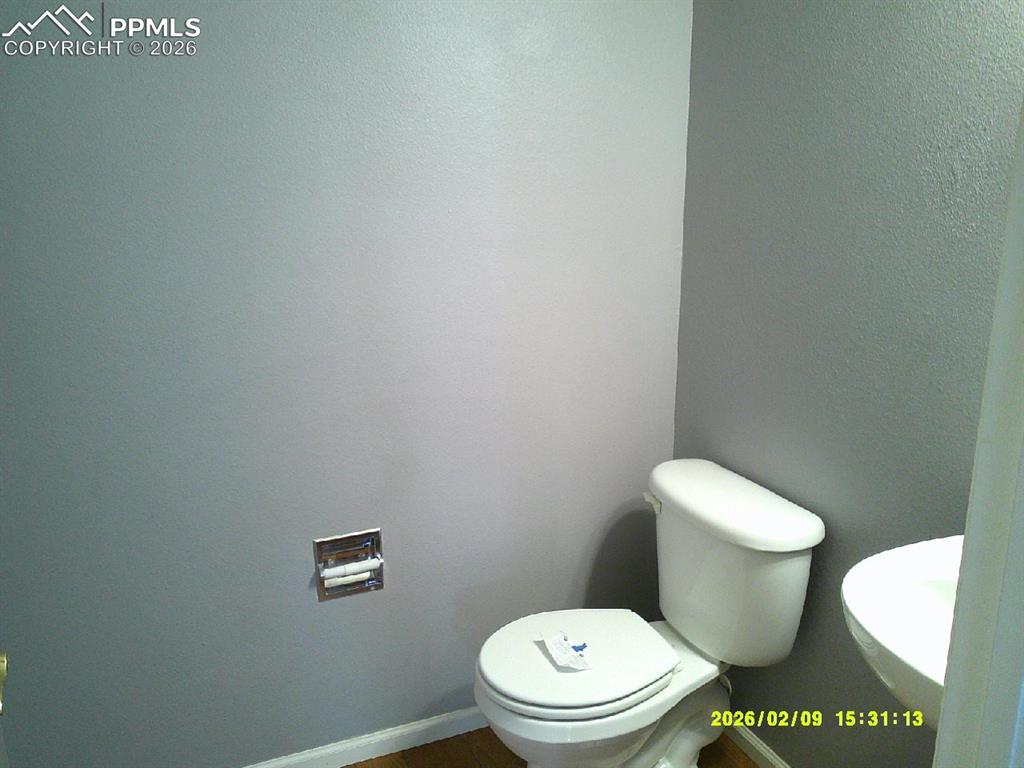 Half bathroom featuring toilet and a textured wall
