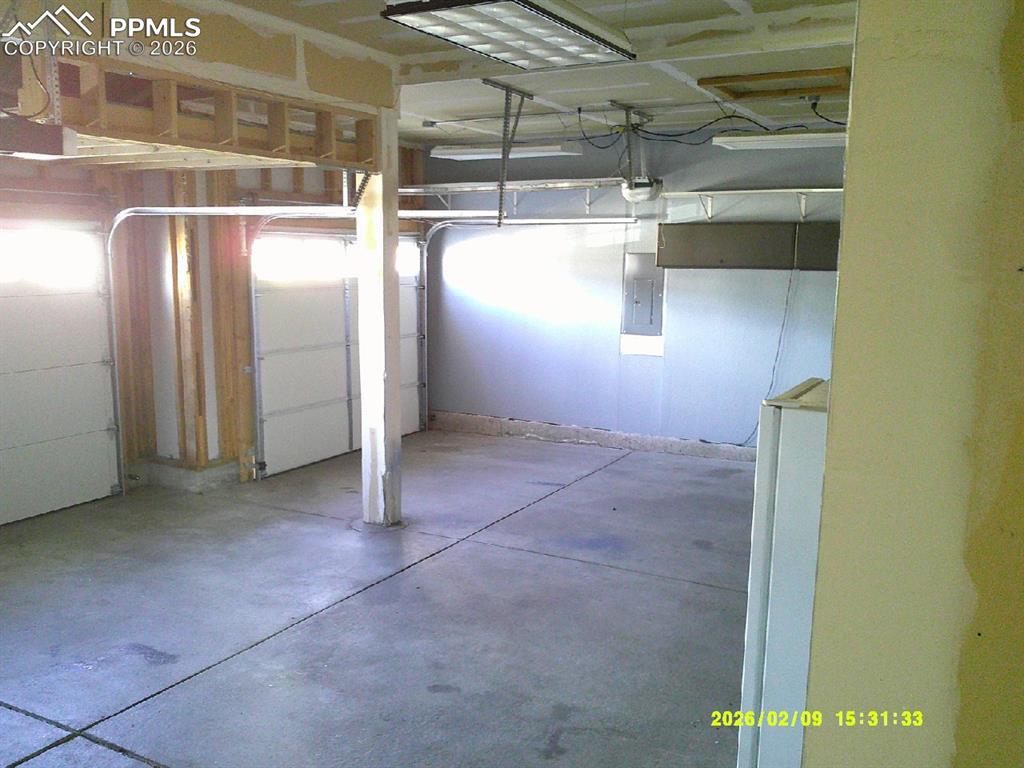 Garage with electric panel and freestanding refrigerator