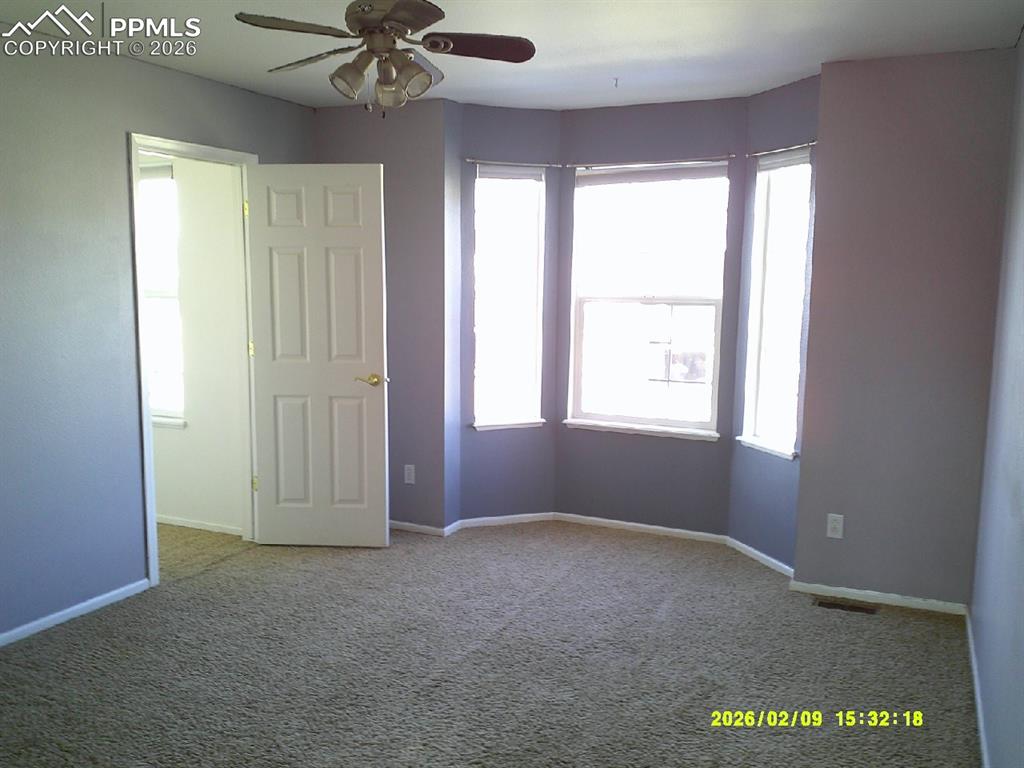 Carpeted spare room with a ceiling fan and baseboards