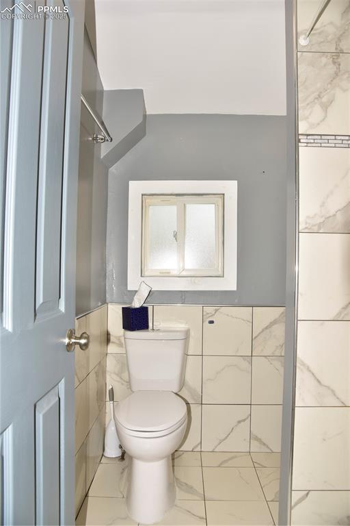 Bathroom featuring toilet and marble finish floors