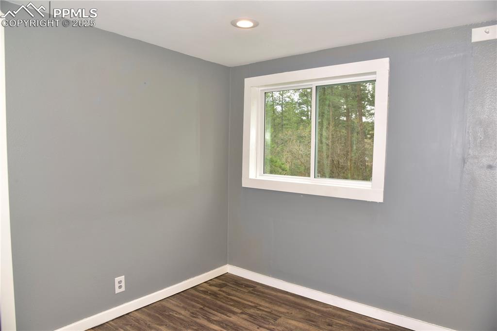 Spare room featuring baseboards, dark wood-style flooring, and recessed lighting