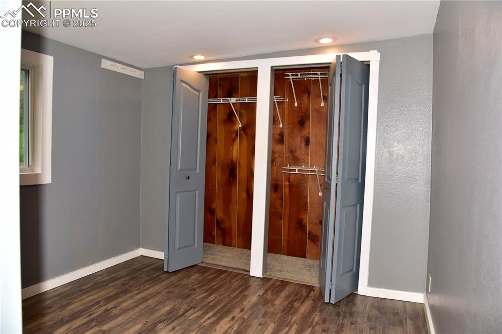 Unfurnished bedroom with dark wood-style floors, two closets, baseboards, and recessed lighting