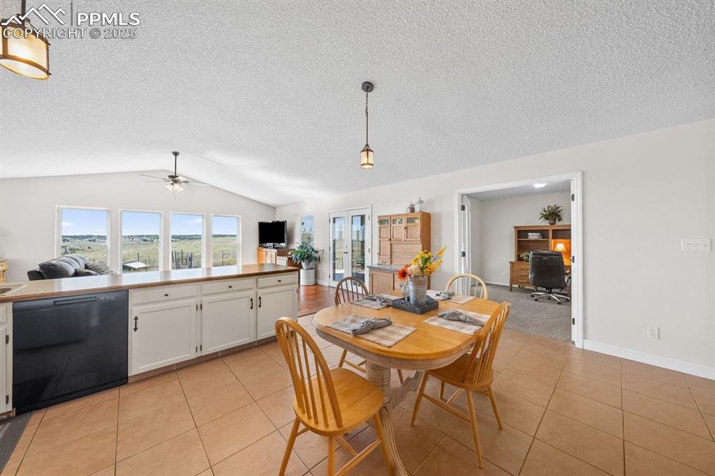 Dining area featuring vaulted ceiling, light tile floors and a ceiling fan