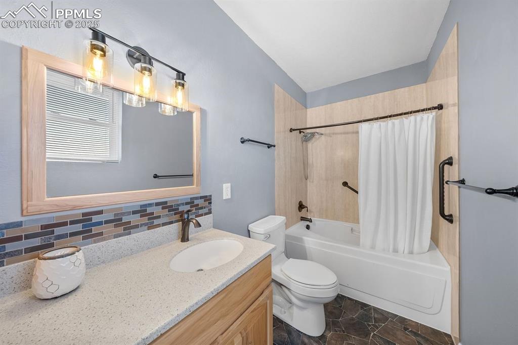 Bathroom featuring shower / tub combo,  with jetted and heated tub, vanity, backsplash and cabinet