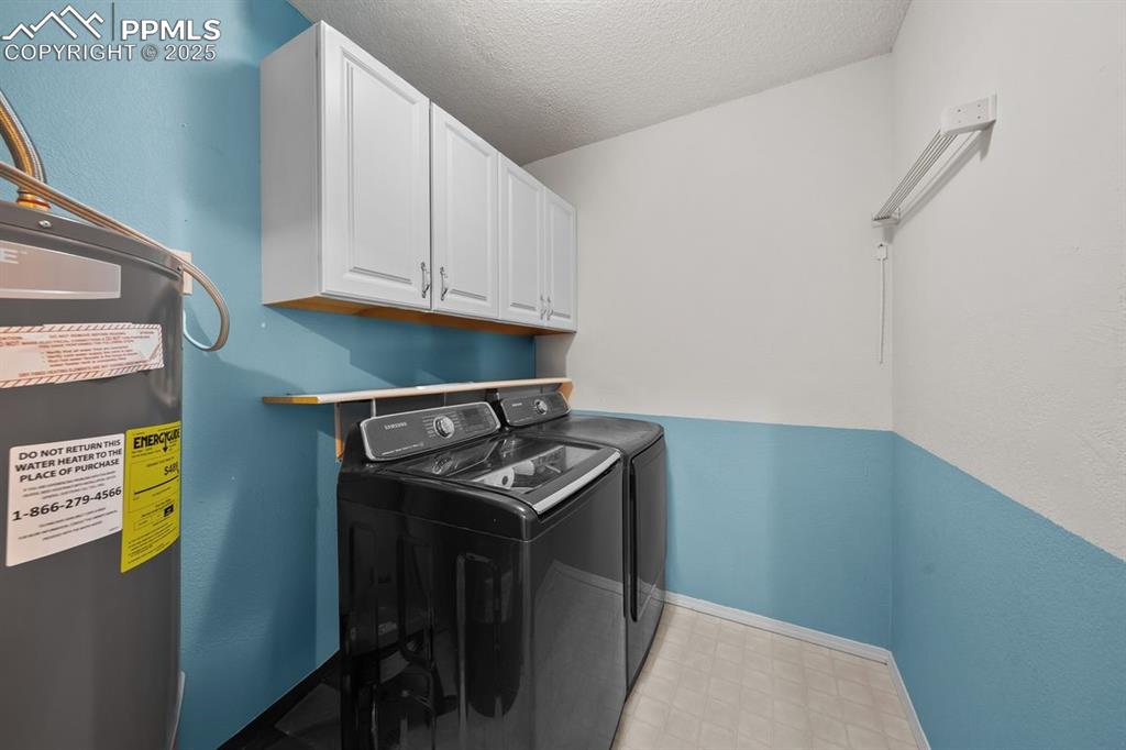 Laundry room featuring water heater and cabinet space