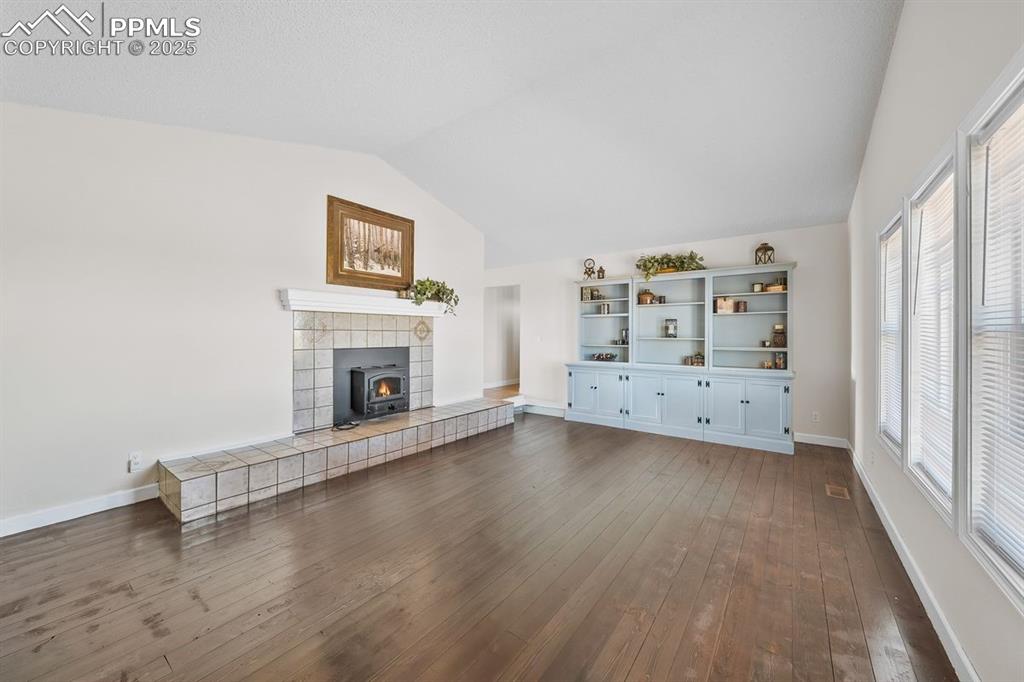 Living room with vaulted ceiling, wood floors and wood stove
