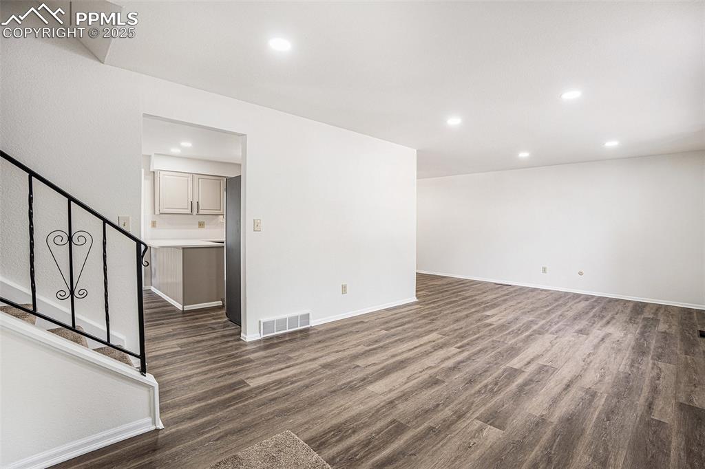 Unfurnished living room featuring recessed lighting and dark wood-style flooring