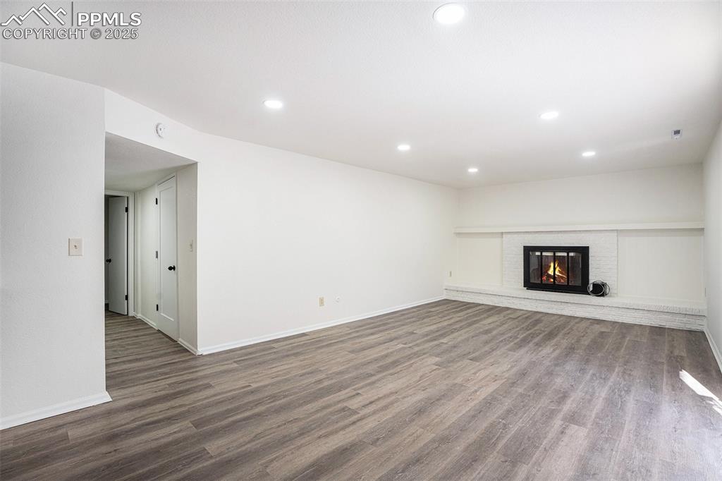 Unfurnished living room featuring wood finished floors, a fireplace, and recessed lighting