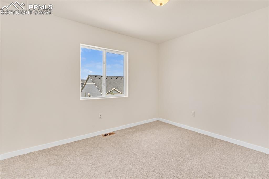 Carpeted spare room featuring baseboards