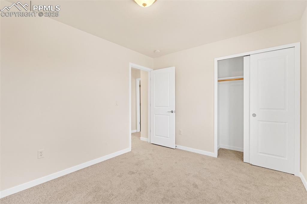 Unfurnished bedroom with light carpet and a closet