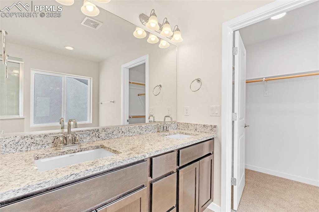 Bathroom featuring a spacious closet, double vanity, recessed lighting, and light colored carpet