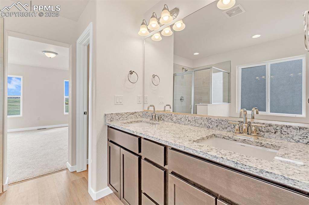 Bathroom with light wood-type flooring, a stall shower, and double vanity