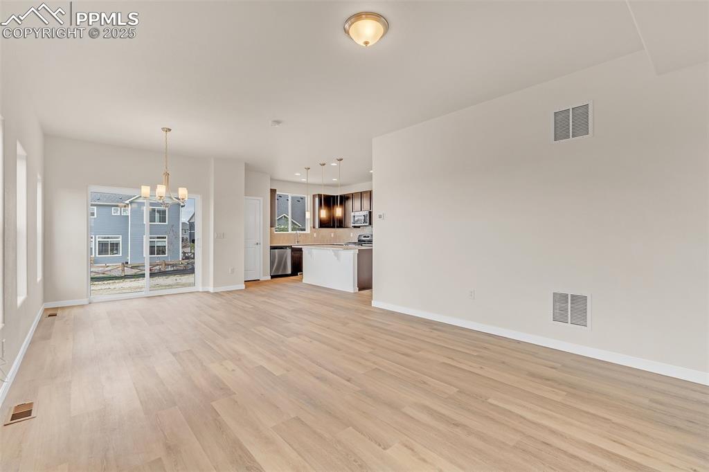Unfurnished living room with a chandelier and light wood-type flooring